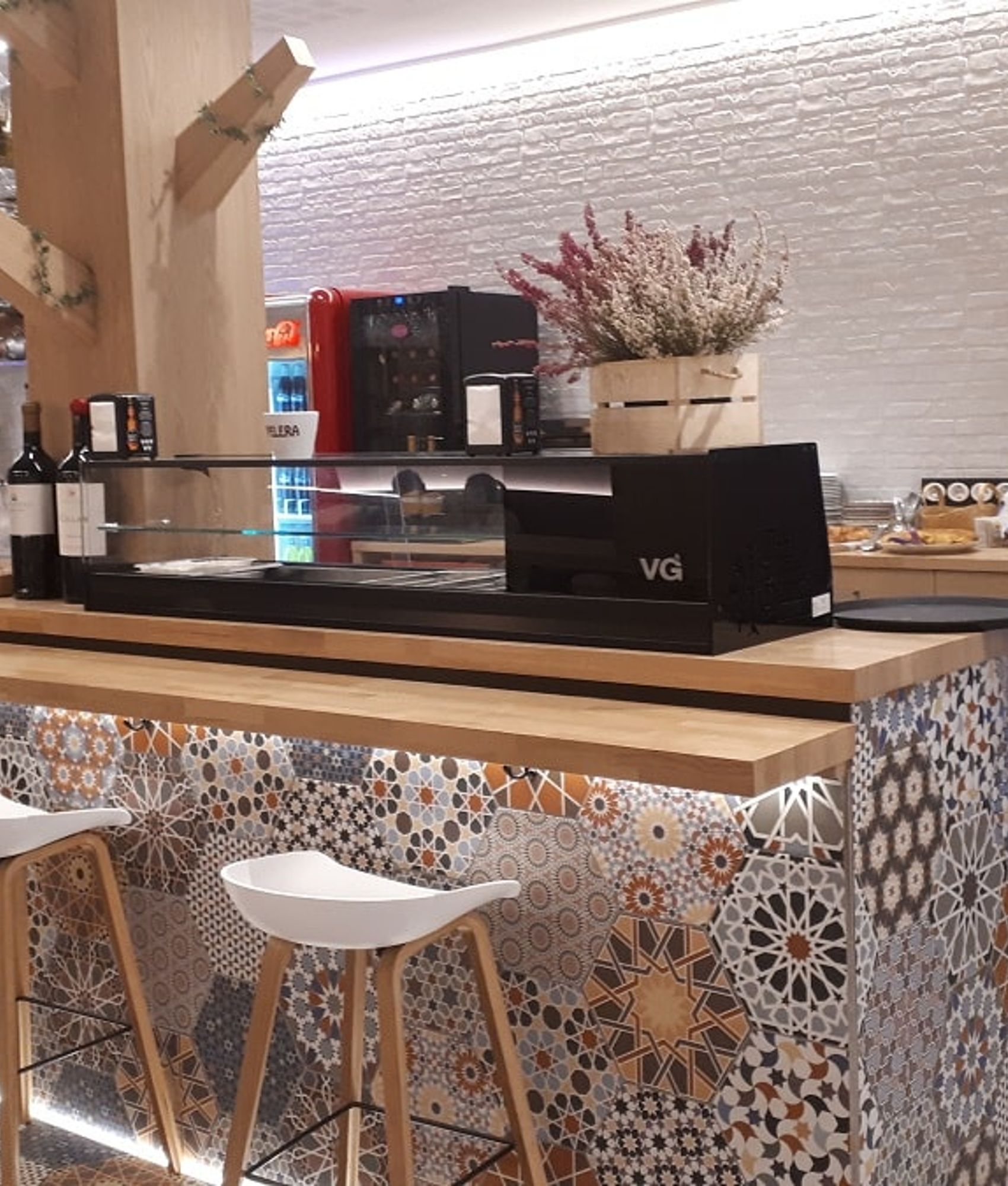 Carreau de ciment terracotta avec motifs géométriques 30x30 cm sur un bar dans une caféterie aux tons bois et blancs, détails de