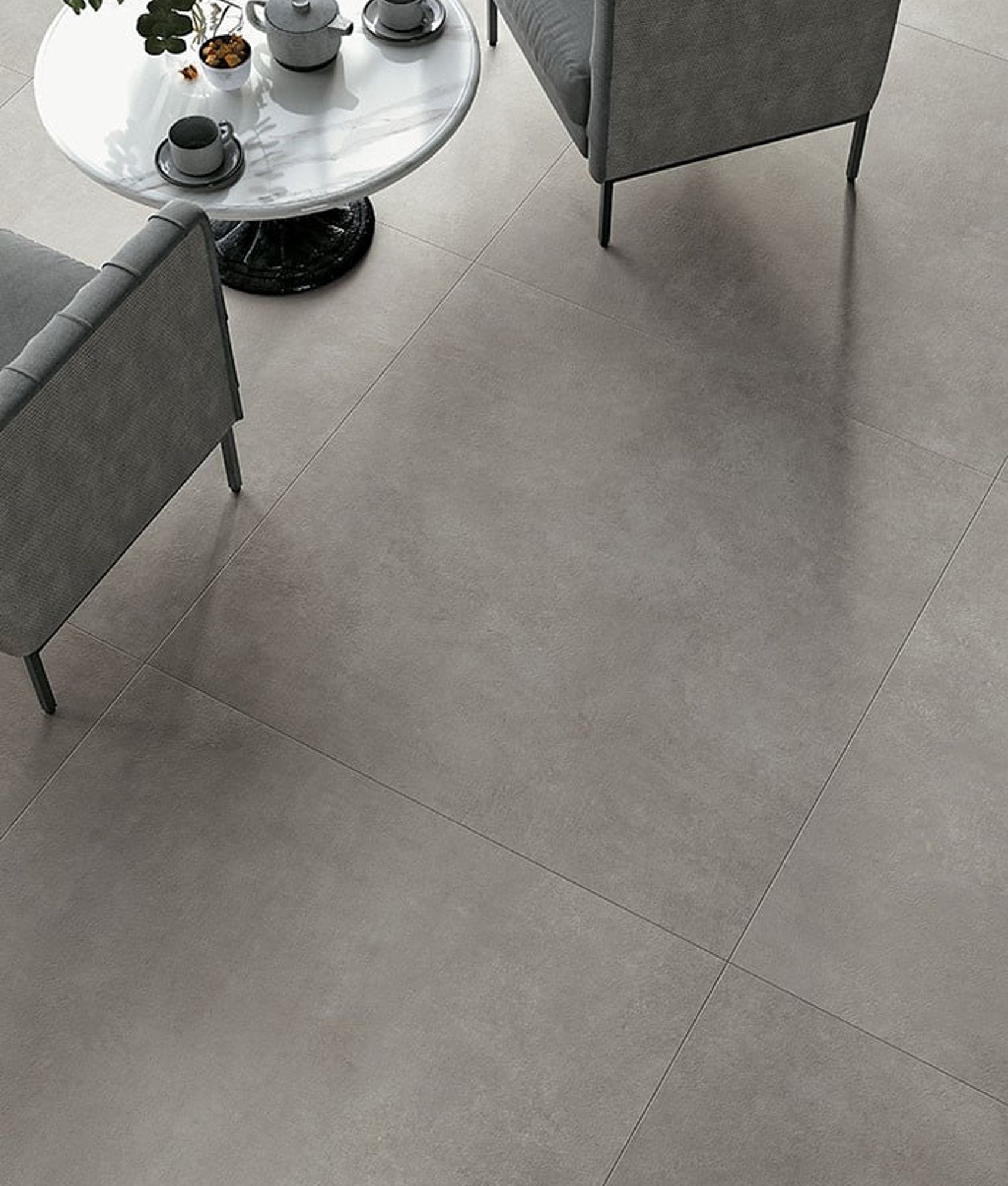 Carrelage effet pierre gris uniforme 60x60 cm dans un salon moderne avec mobilier gris et table blanche