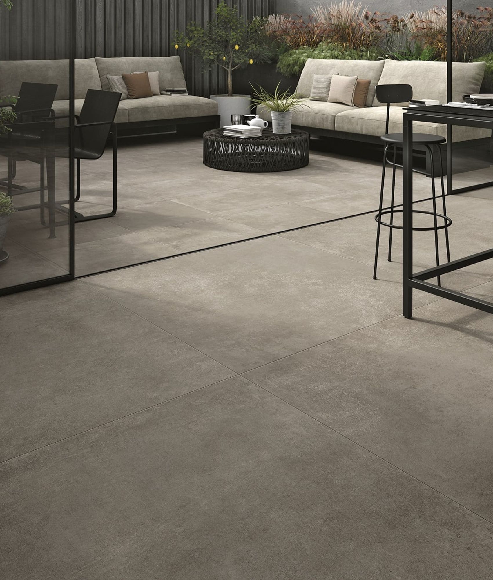 Carrelage effet pierre gris nuancé 60x60 cm dans un salon extérieur ton sur ton avec mobilier de jardin et plantes