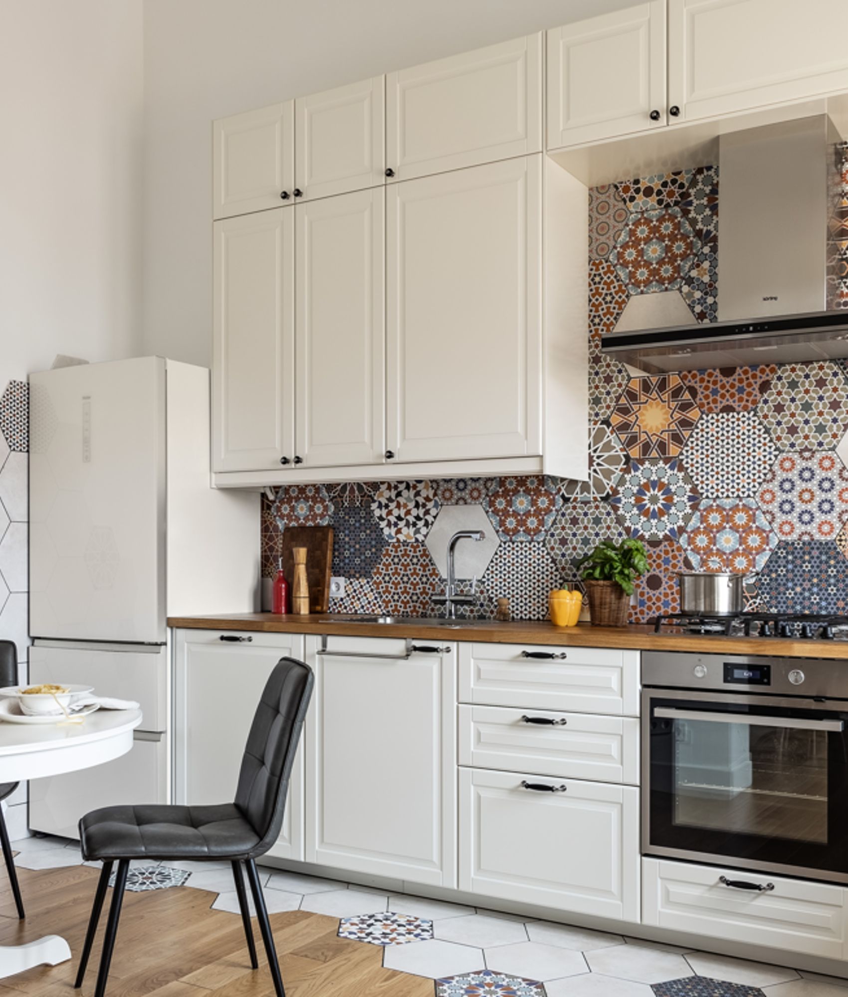 Carreau de ciment terracotta avec motifs hexagonaux 30x30 cm dans une cuisine blanche et bois avec table, chaises et suspensions