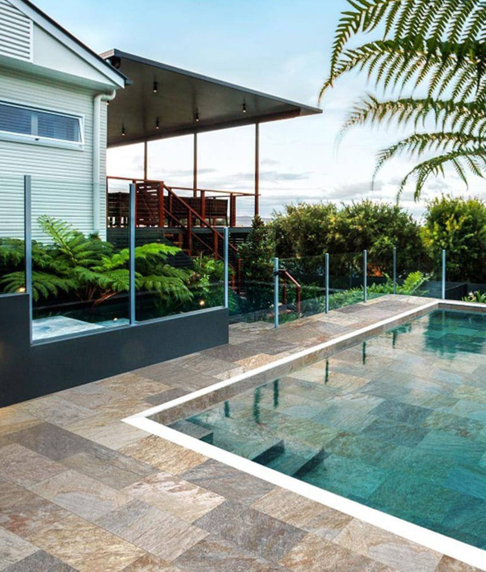 Carrelage effet pierre marron nuances de beige 30x60 cm sur terrasse extérieure verdure et piscine