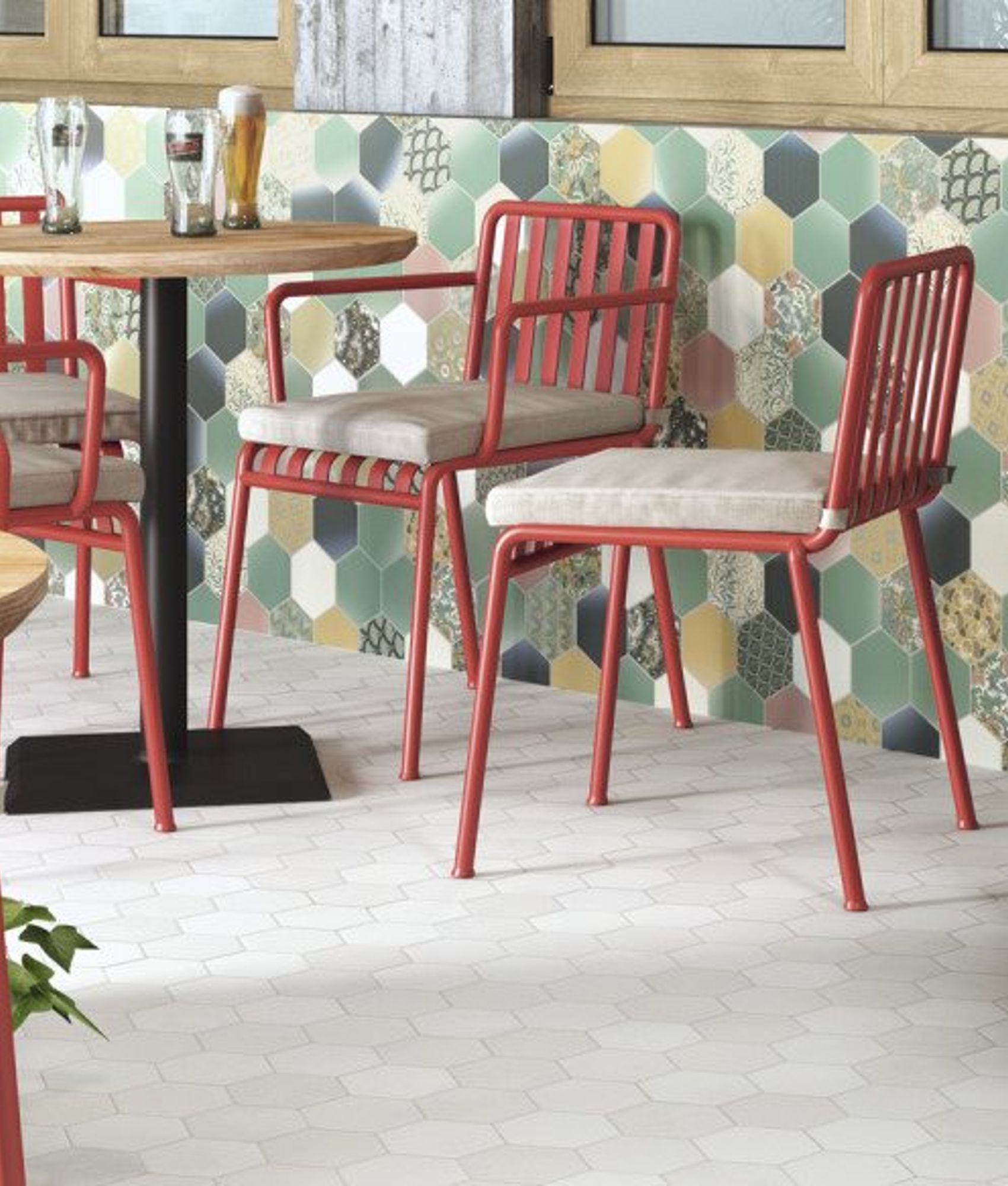 Carrelage uni blanc dans une salle à manger aux chaises rouges, mur multicolore, plantes vertes, éclairage naturel