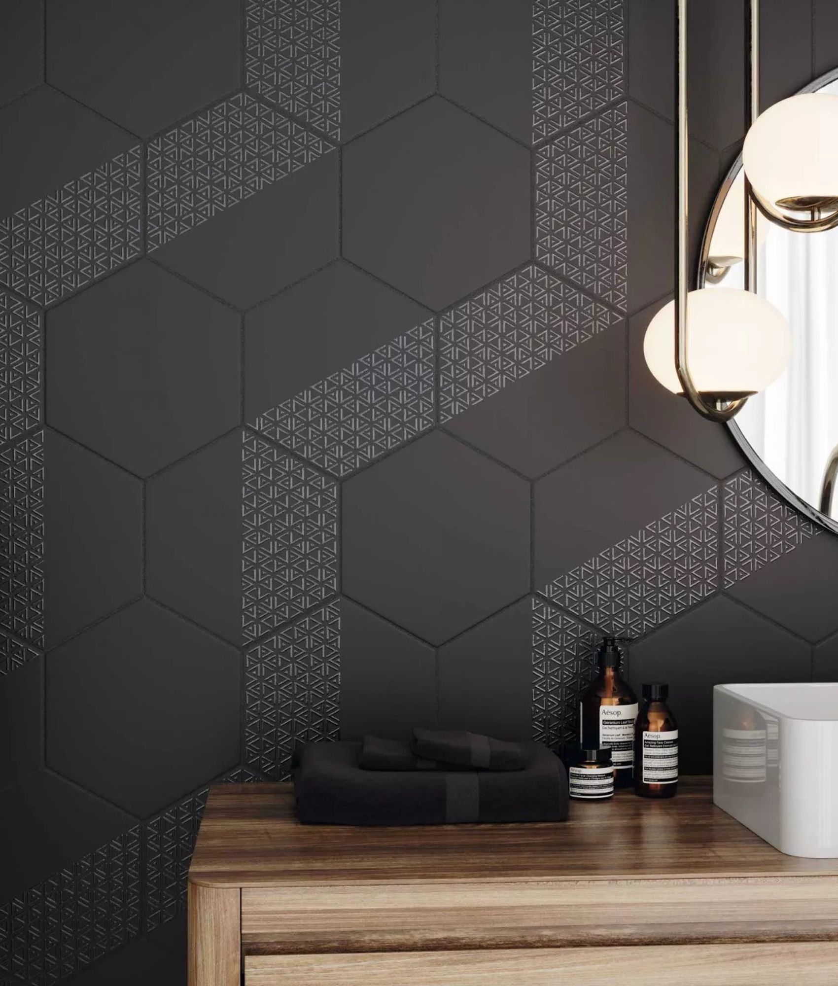 Carrelage uni noir avec motifs géométriques dans une salle de bain épurée avec des éléments blancs et bois, plantes vertes et éc