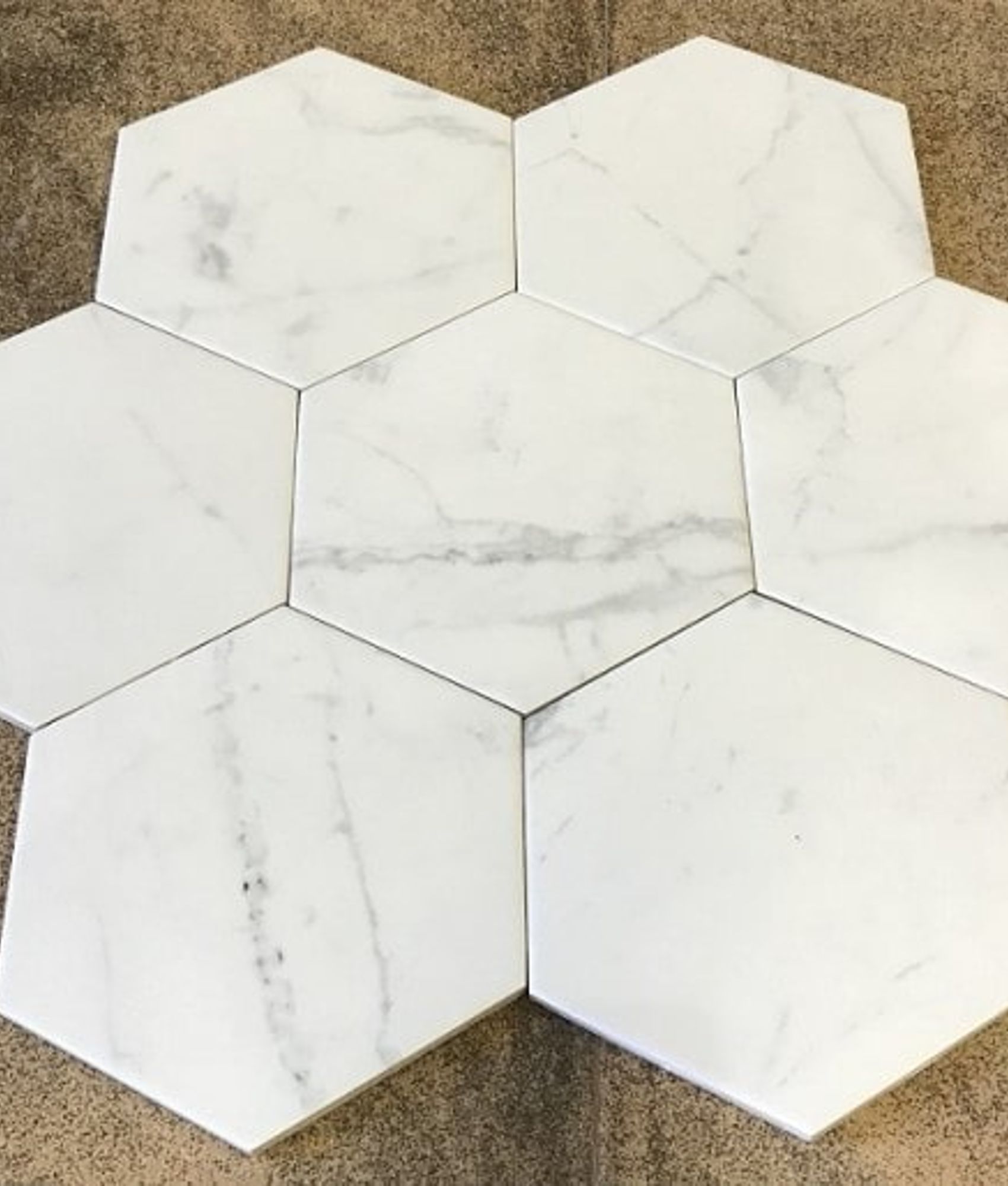 Carrelage aspect marbre blanc avec veines grises, forme hexagonale, sur fond beige.