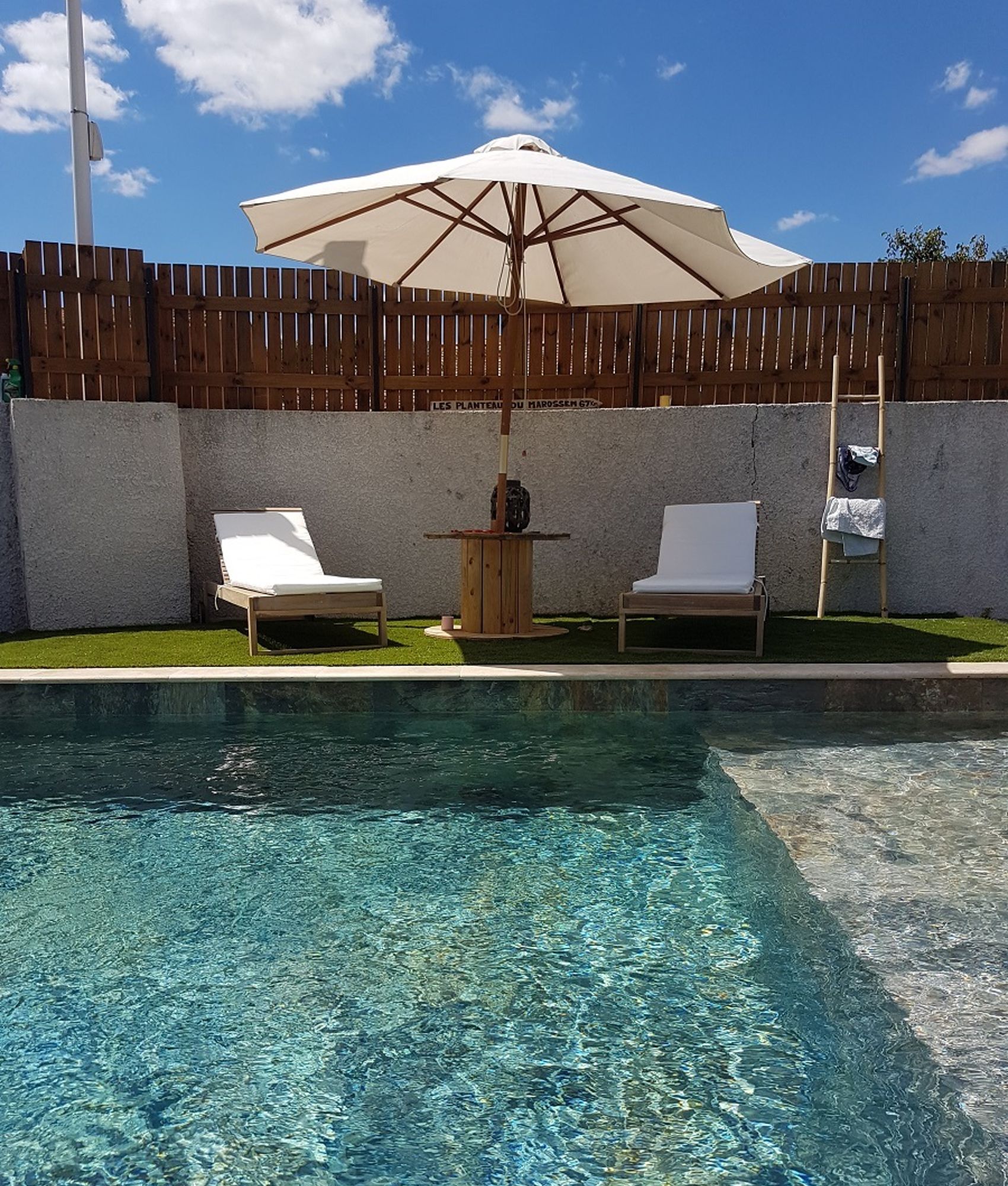 Carrelage Pierre Terracotta sur une terrasse extérieure avec mobilier blanc et parasol, couleurs naturelles et gazon artificiel