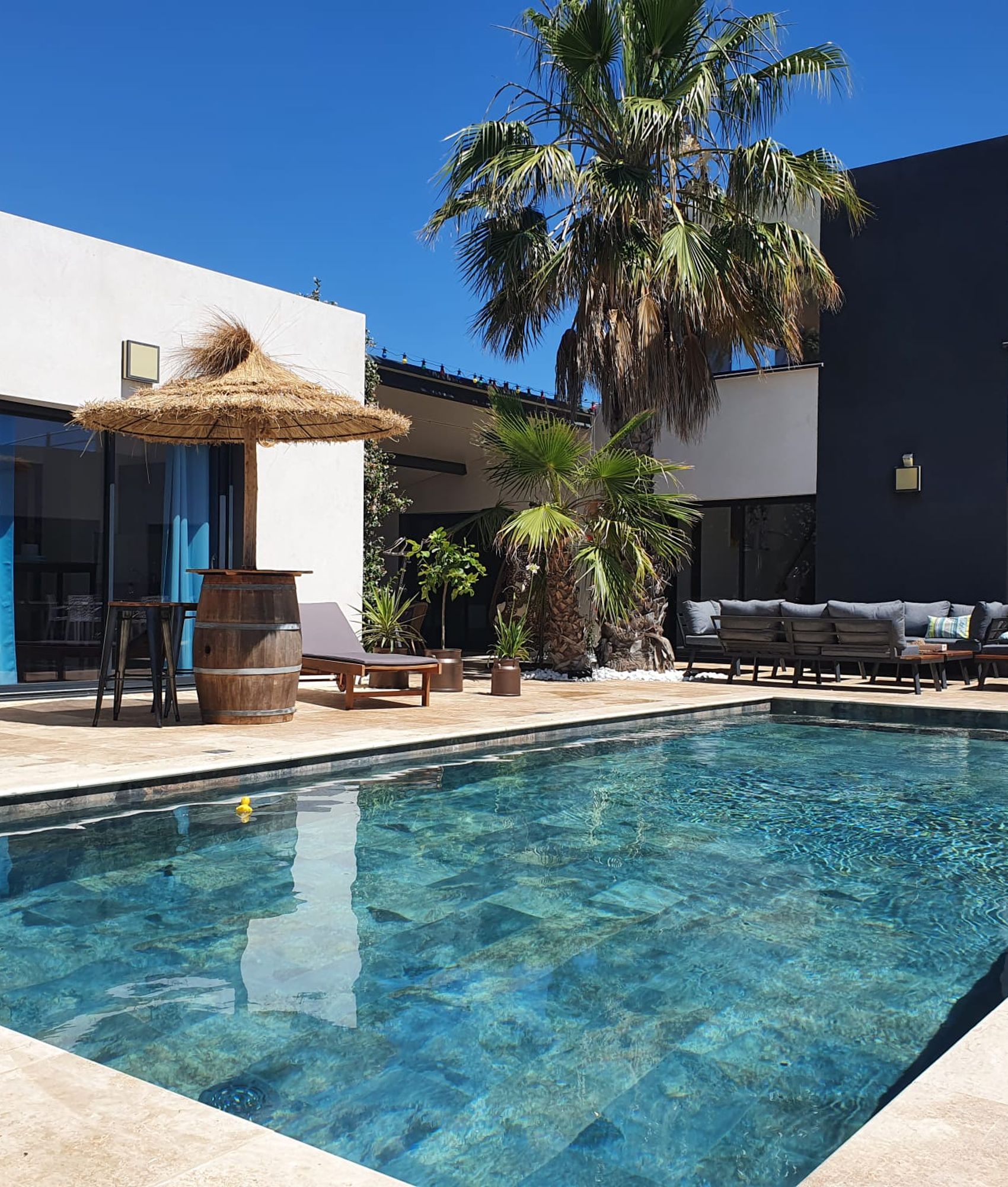 Carrelage aspect pierre couleur terracotta dans un espace extérieur avec piscine entouré de canapés gris et détails verts